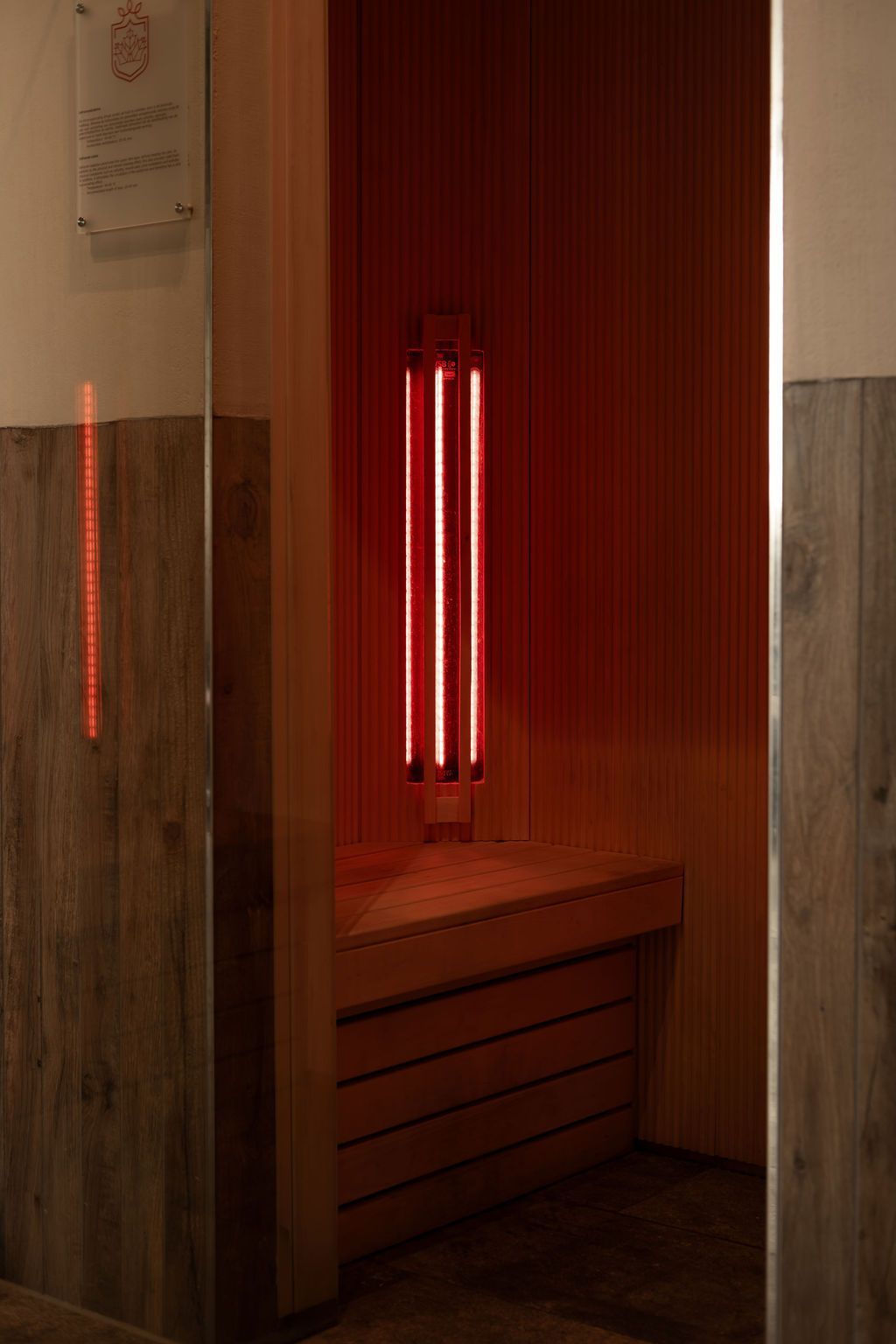 Rood verlichte houten saunabank in een kleine, afgesloten nis.