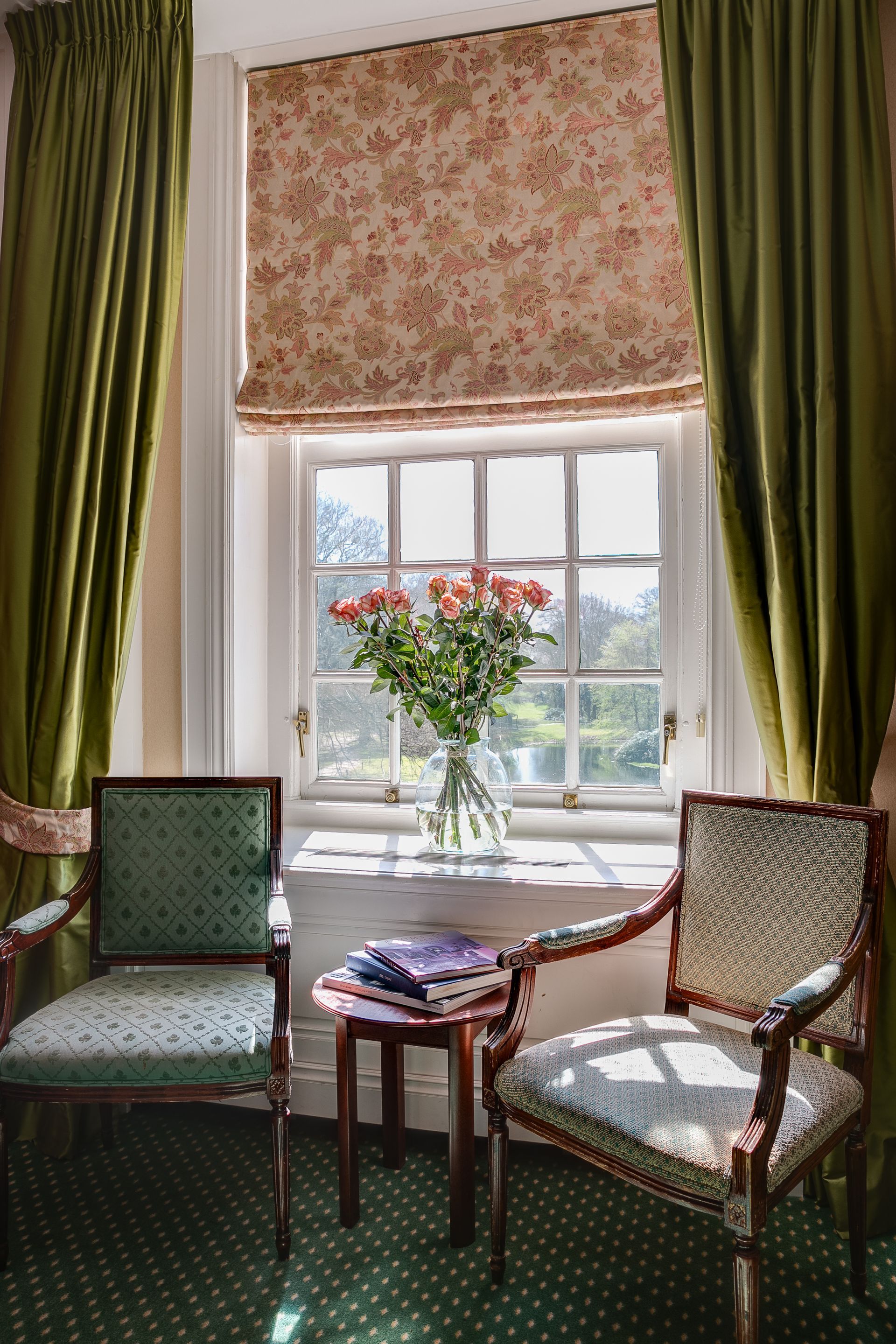 Cozy sitting nook with two chairs, small table, and a vase of flowers by a bright window