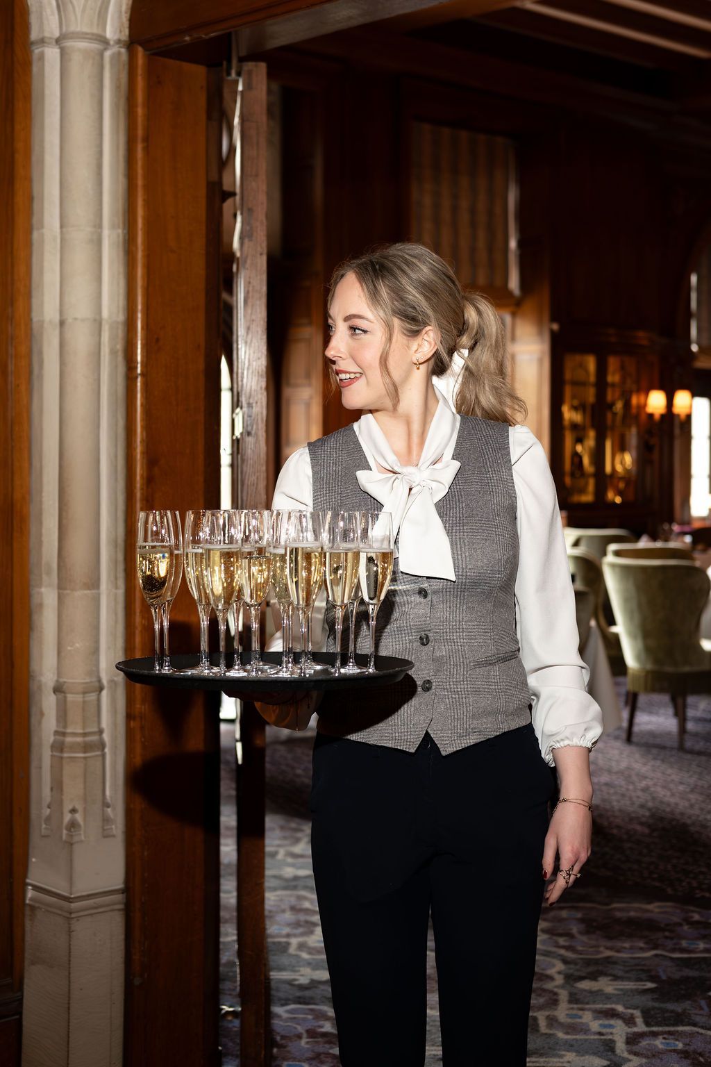 Waitress carrying a tray of champagne glasses in an elegant restaurant hallway