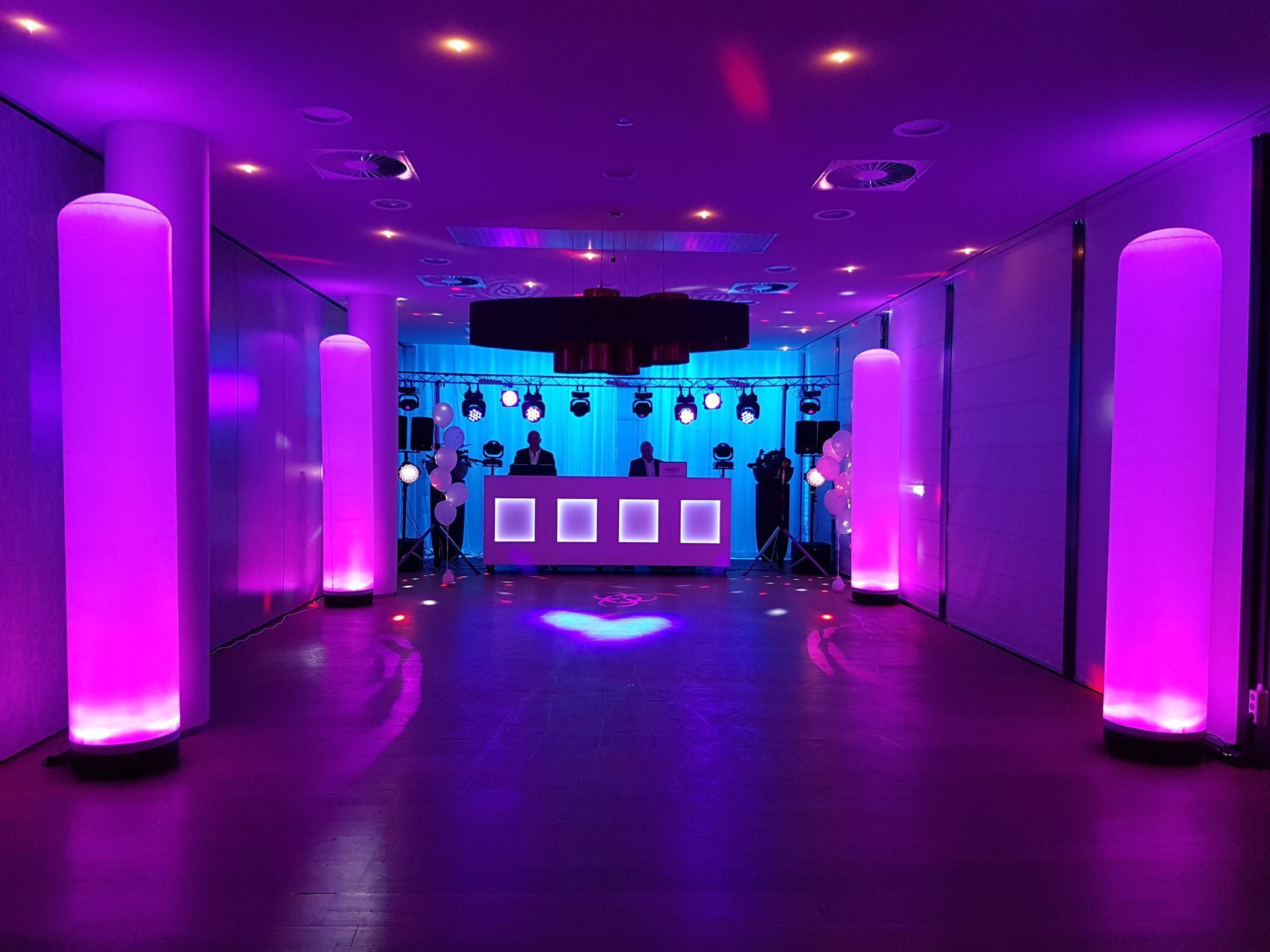 Purple-lit nightclub interior with glowing columns and a blue-lit bar at the back