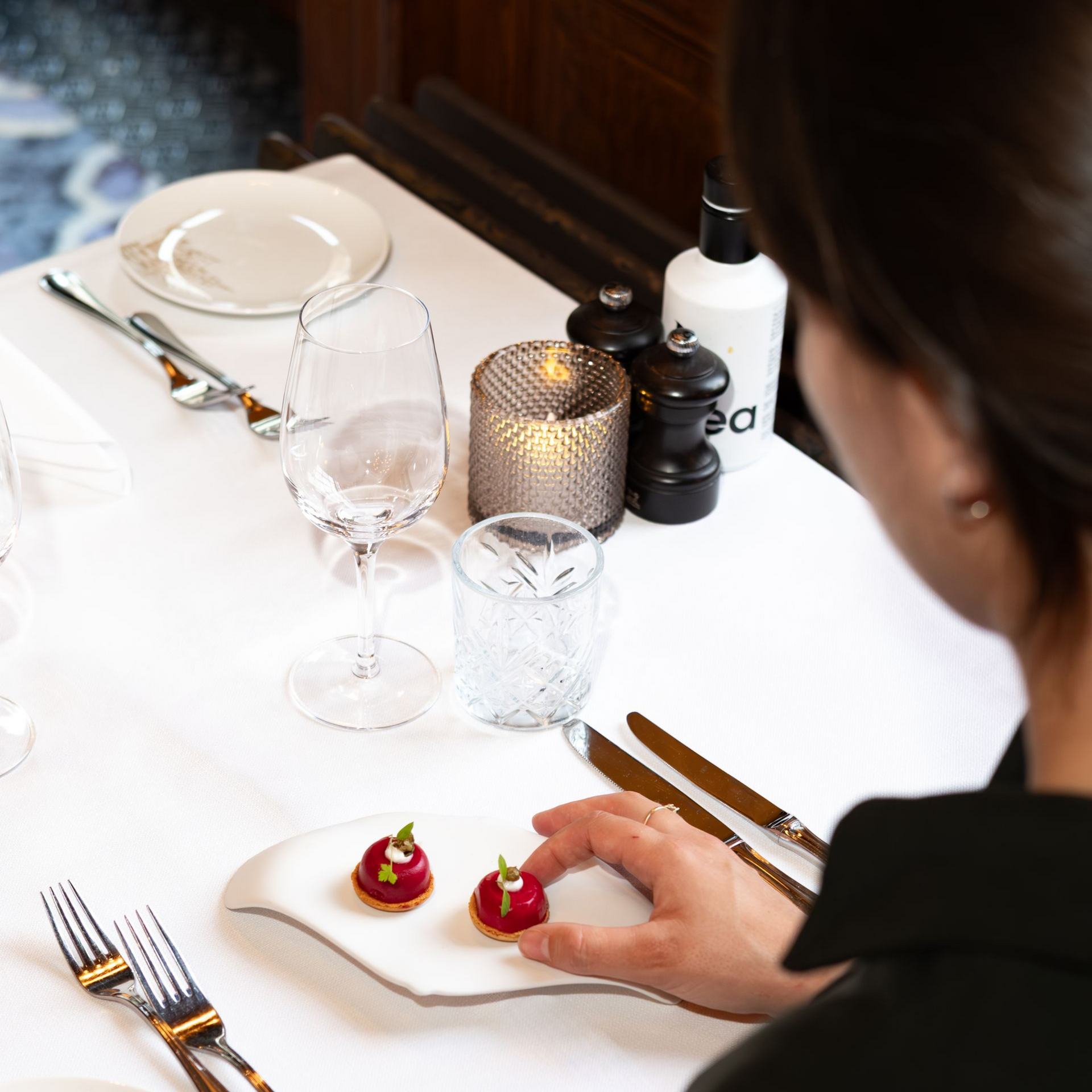 Dining table set for a meal, with a hand placing dessert on a white plate