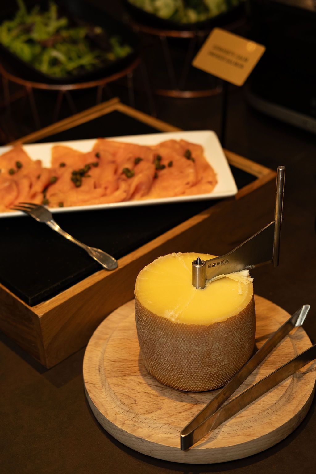 Dessertpresentatie met een taart met gele bovenkant op een houten bord naast een schaal met gebak.