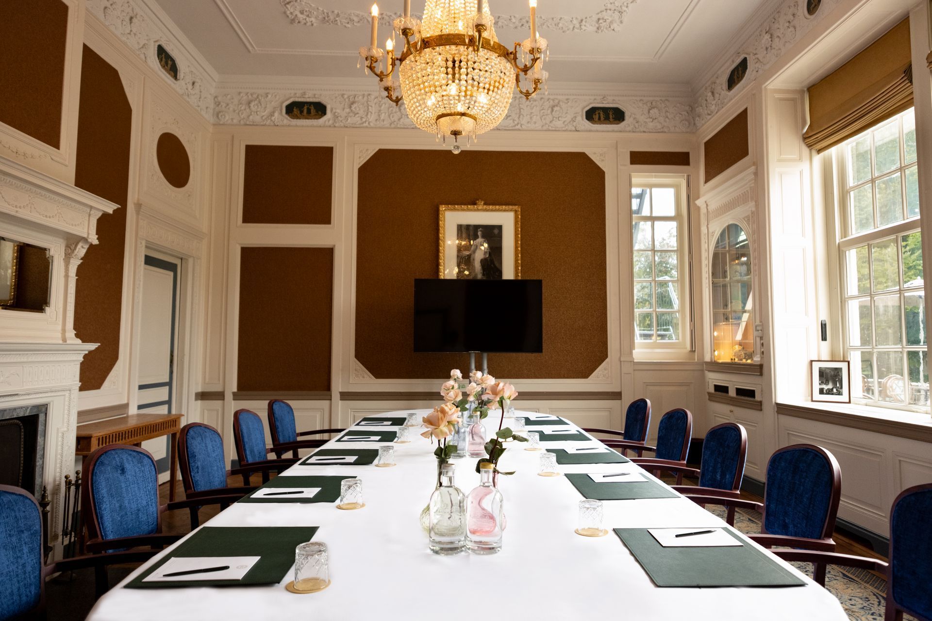 Elegant conference room with a long table, blue chairs, chandelier, and large windows.