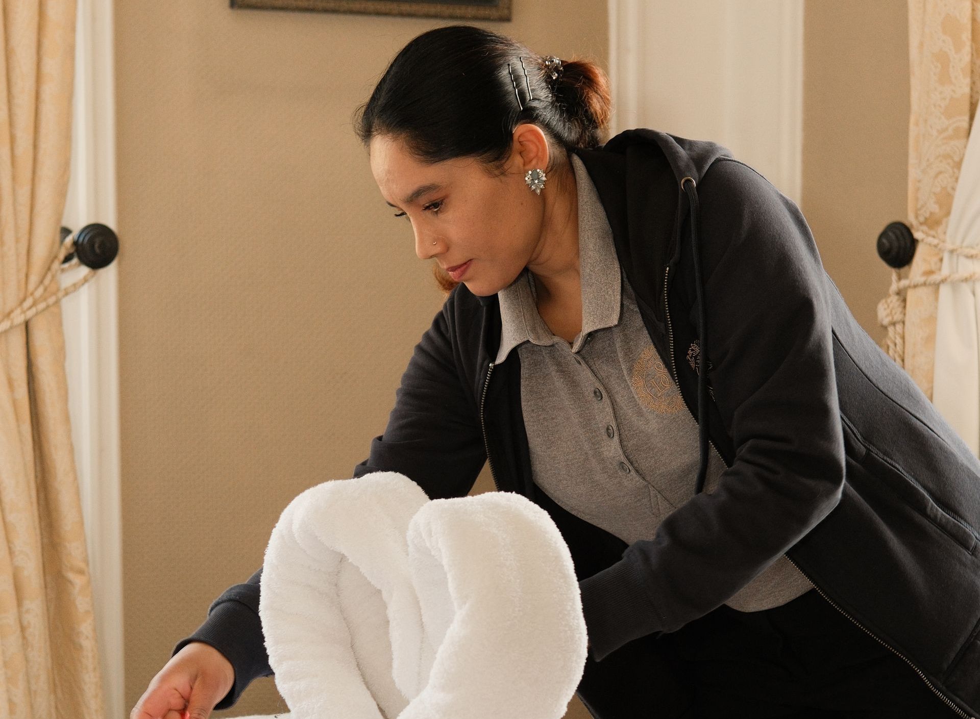 Person kneeling indoors, helping adjust white clothing on a seated child.