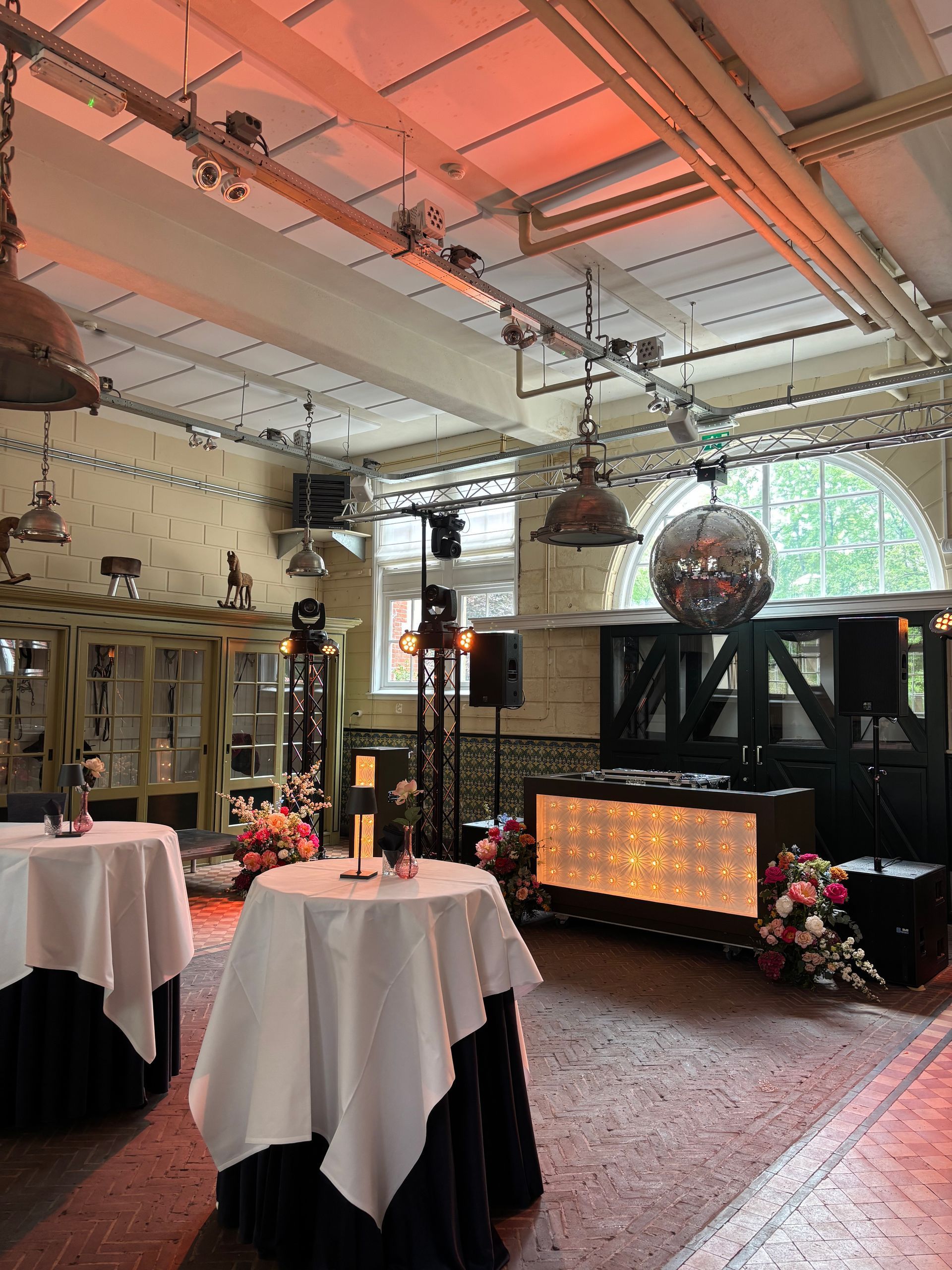 Elegant dining hall with round tables, black chair covers, and warm lighting under exposed beams