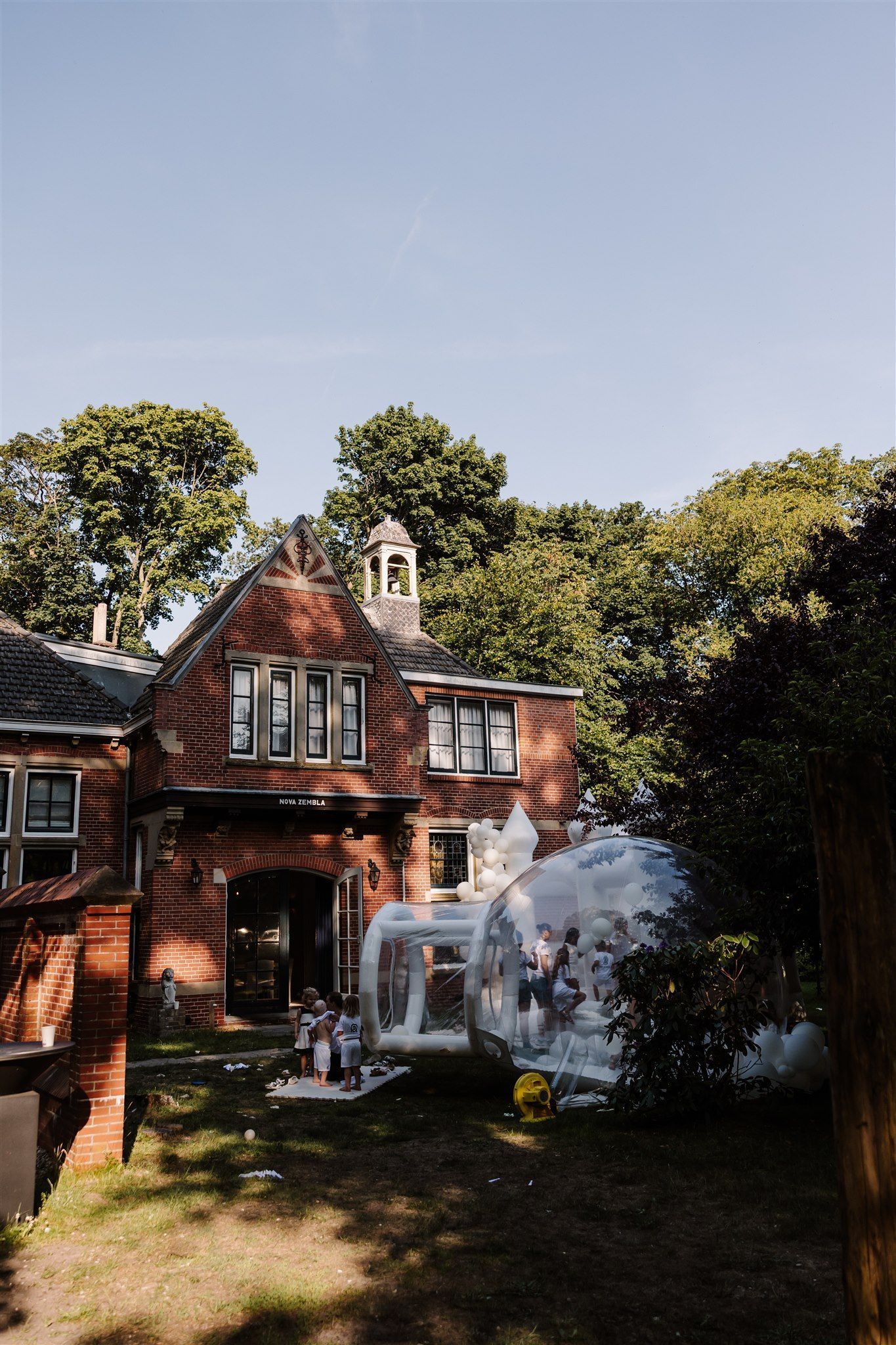Brick house with white porch in a leafy yard on a sunny day