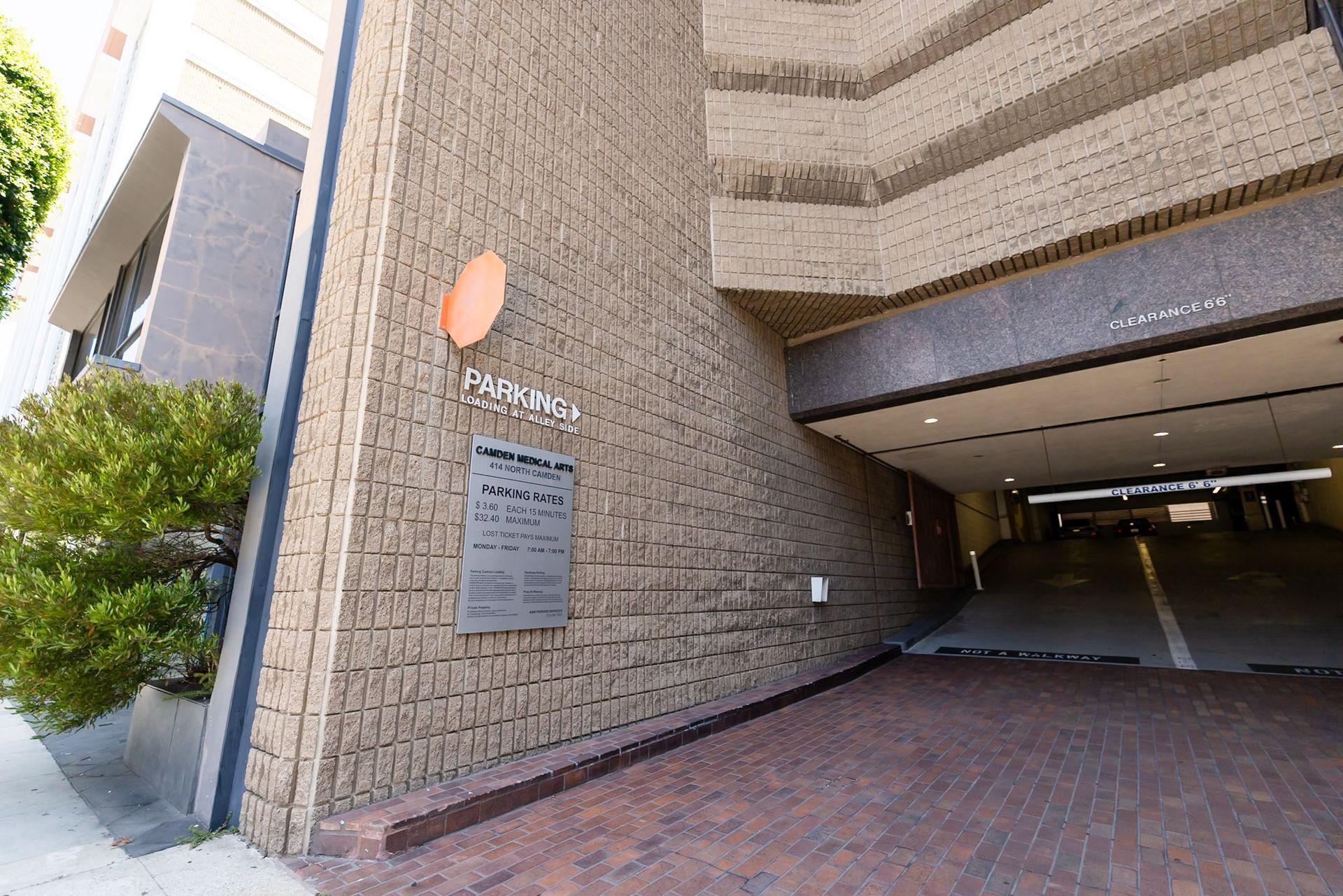 Building entrance with brick walls, sign plaque, and covered parking garage driveway