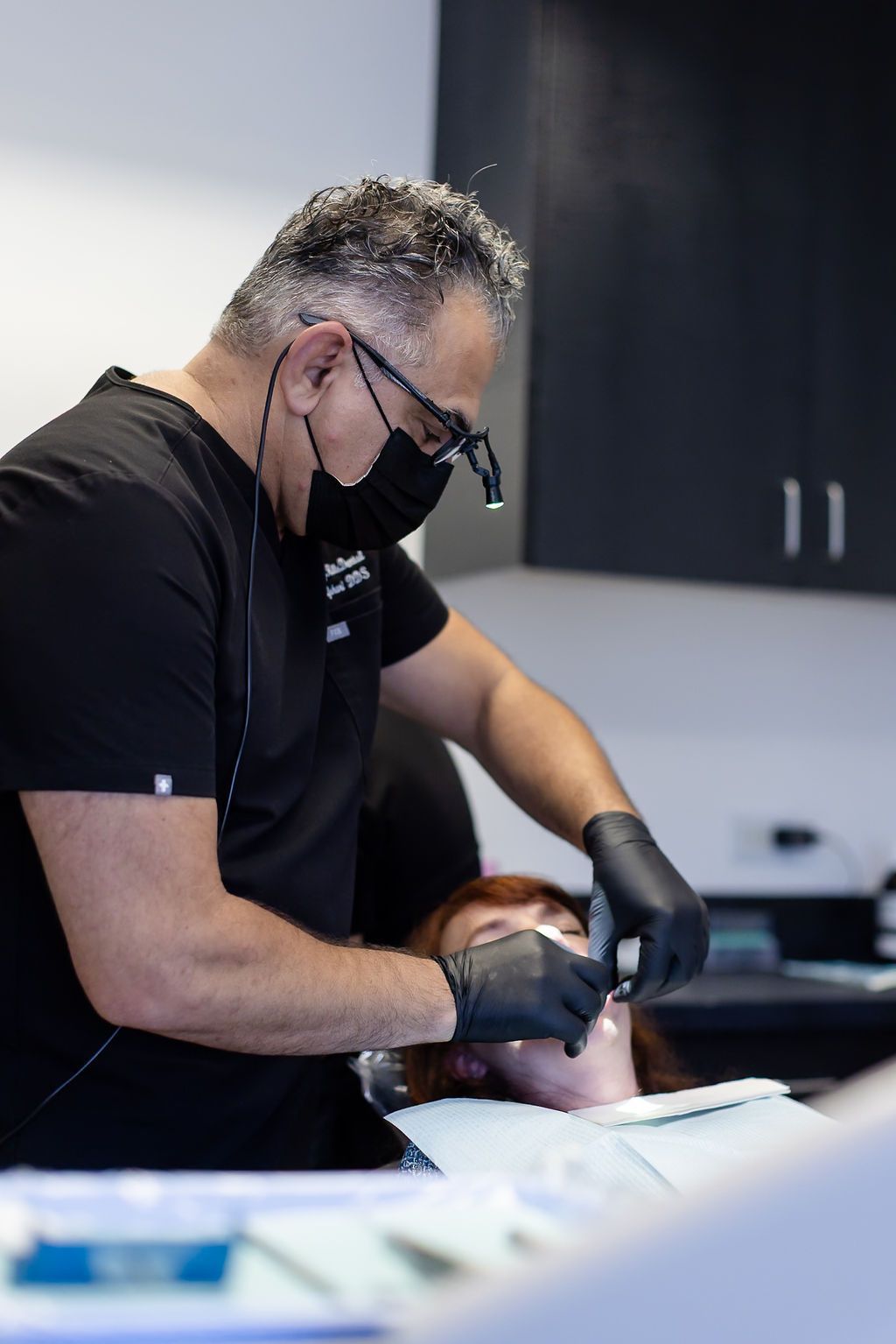 Dentist wearing gloves and mask examining a patient in a clinic room