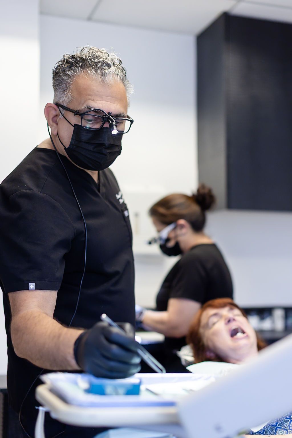 Dentist in black gloves and mask working in a dental office