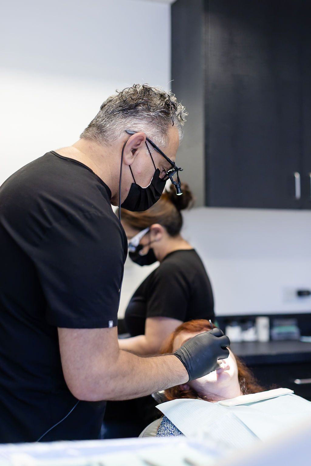 Dentist in black gloves and mask working on a patient in a clinic