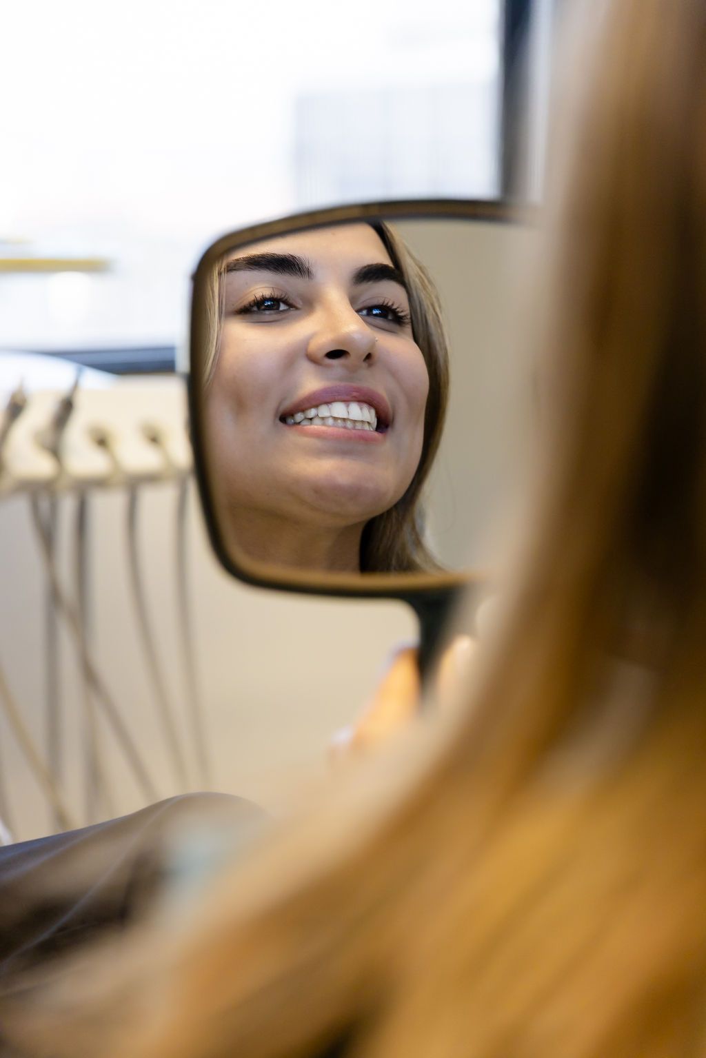 Woman smiling at a mirror in dental in a clinical office