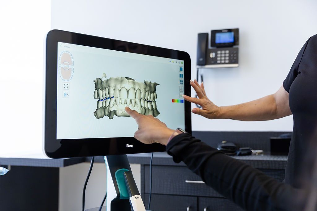 Dentist demonstrating a dental scan on a large touchscreen monitor in a clinical office
