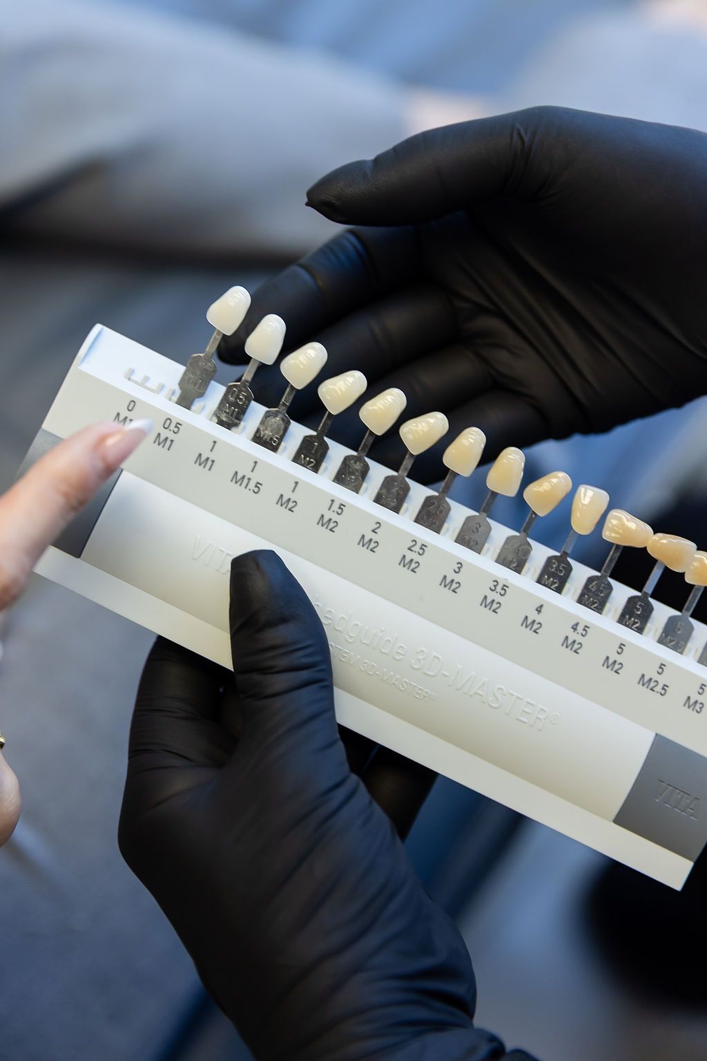 Gloved hands holding a dental shade guide with tooth color samples