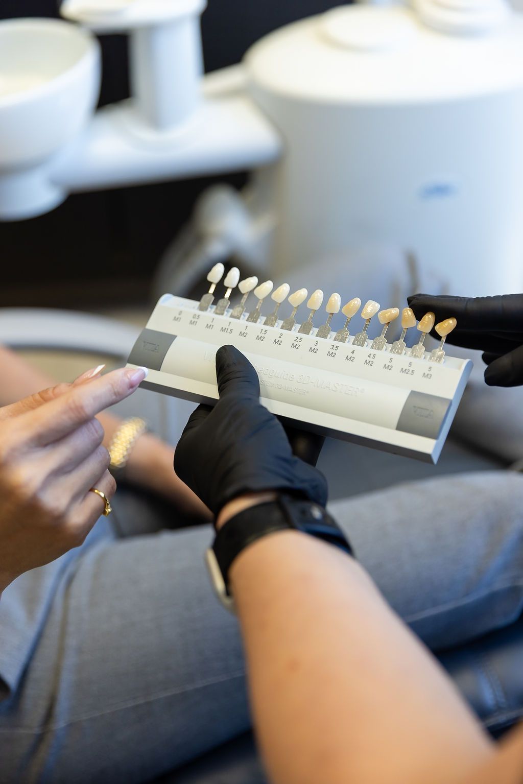 Gloved hands holding a dental shade guide with tooth color samples