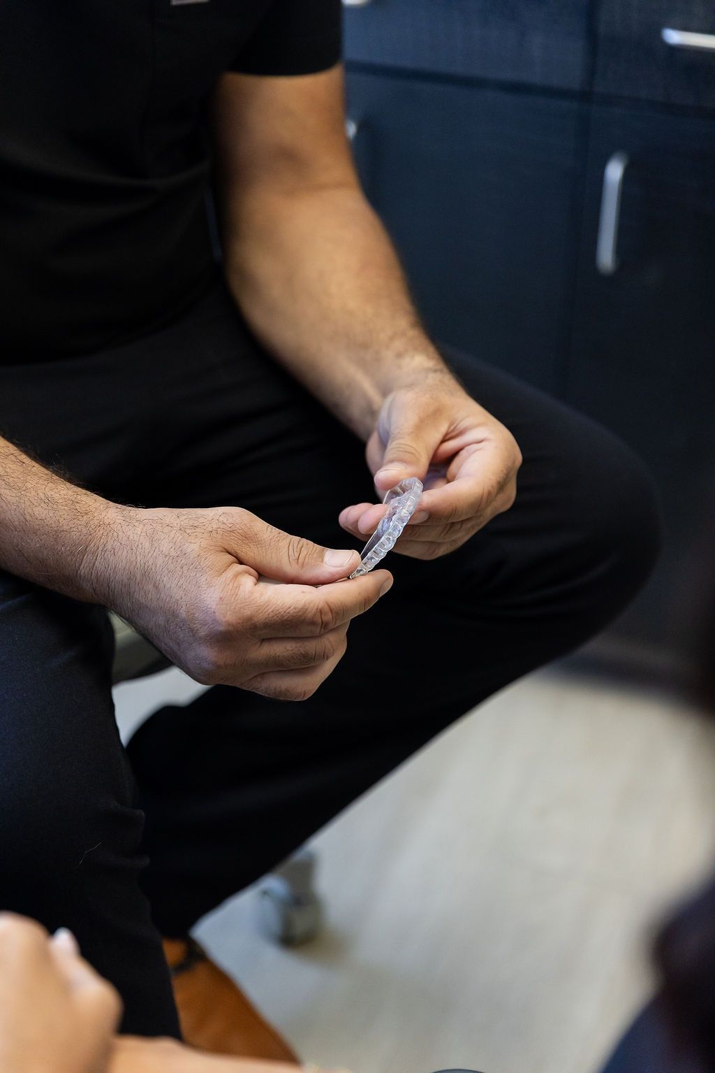Person seated indoors, holding and examining a small object