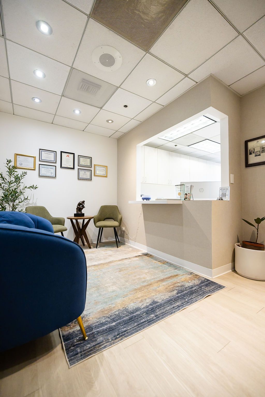 Modern office lounge with blue chairs, wall art, rug, and a reception counter under bright ceiling lights