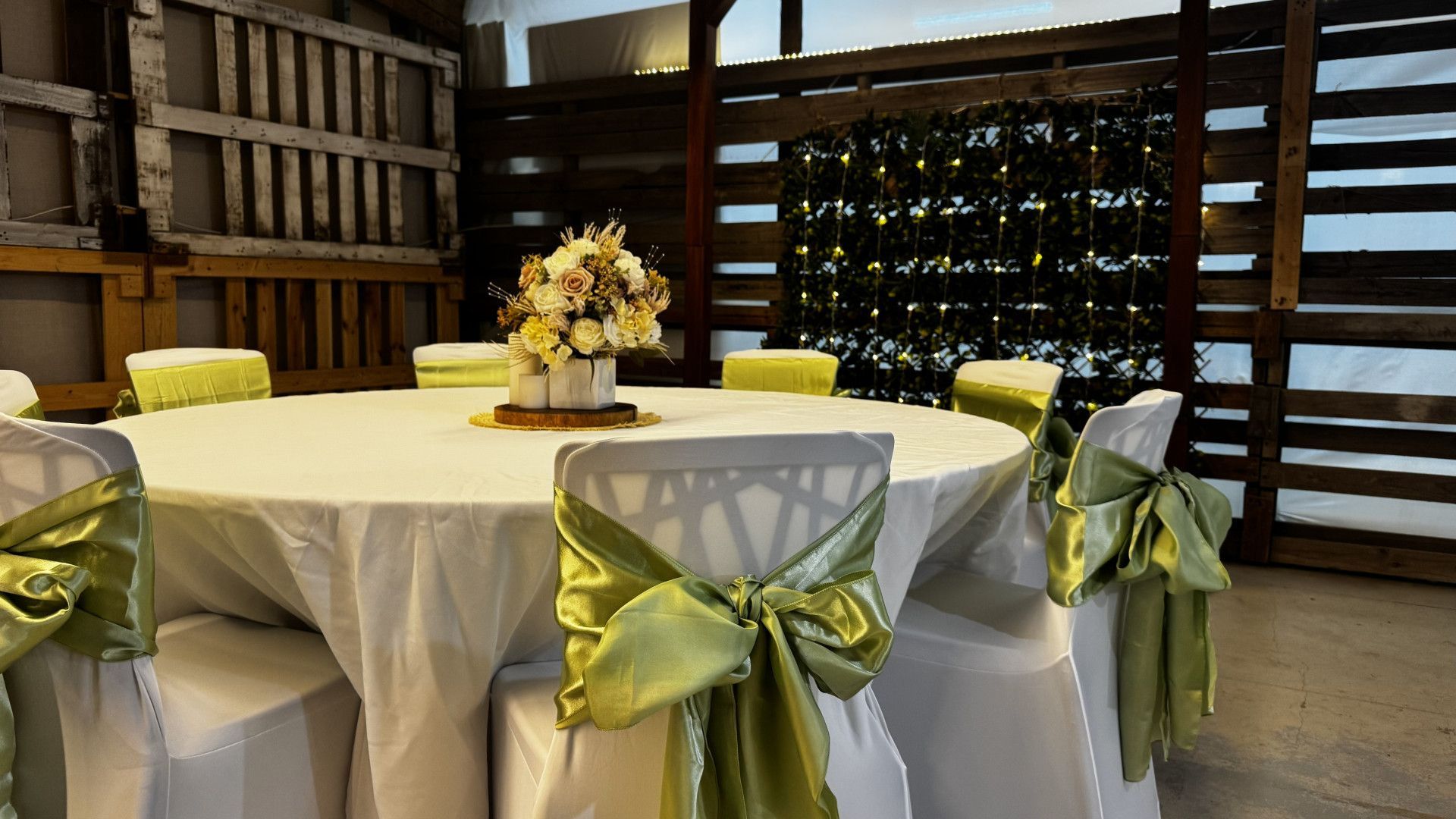 Centerpiece with flowers, candles, and wooden base on a table. Beige and white tones, warm lighting — Rustique on the Coast In Ourimbah, NSW