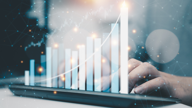 Hand using a tablet with glowing growth chart bars and an upward trend line overlay