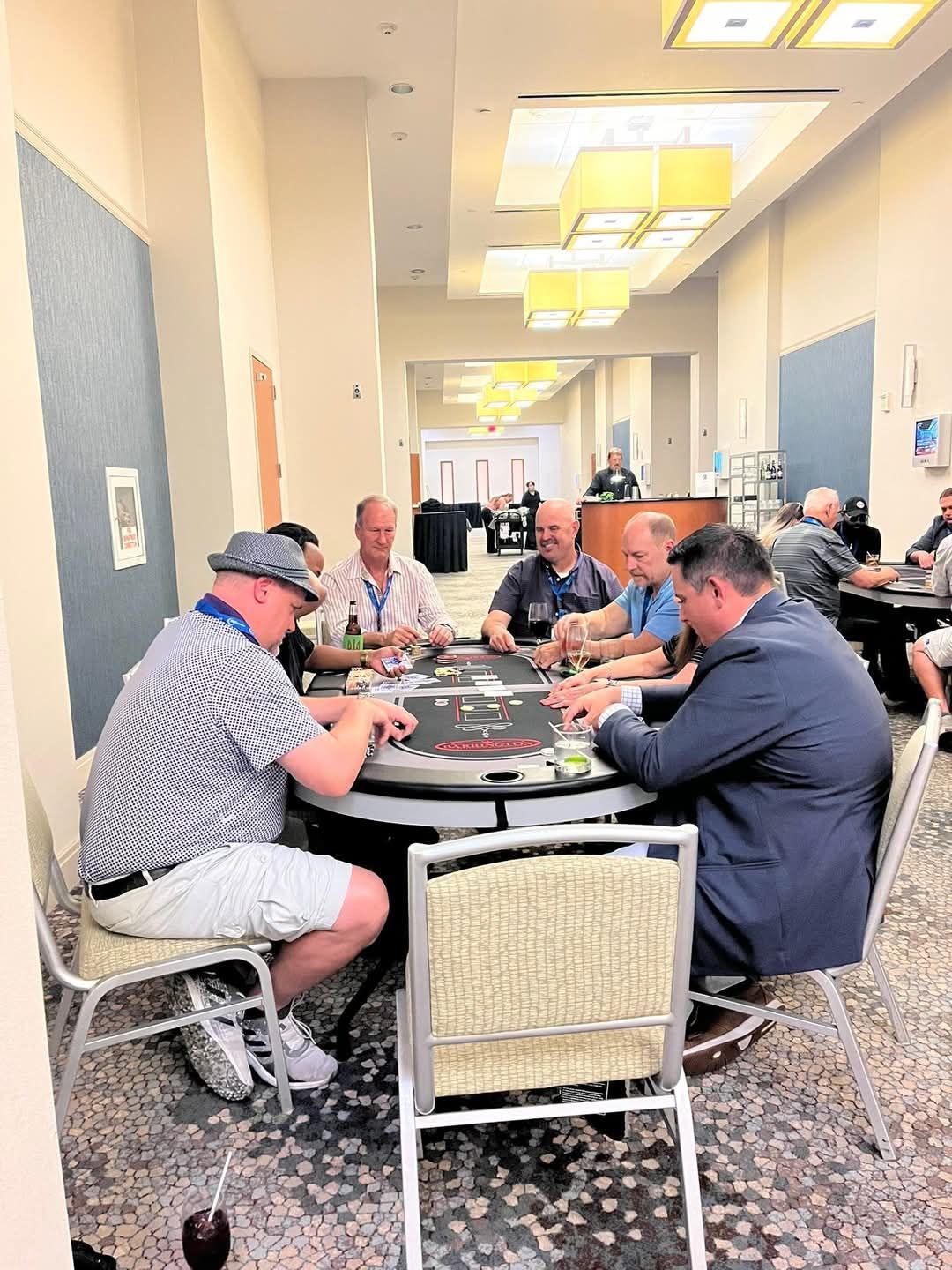 People seated around a poker table in a bright hotel conference room