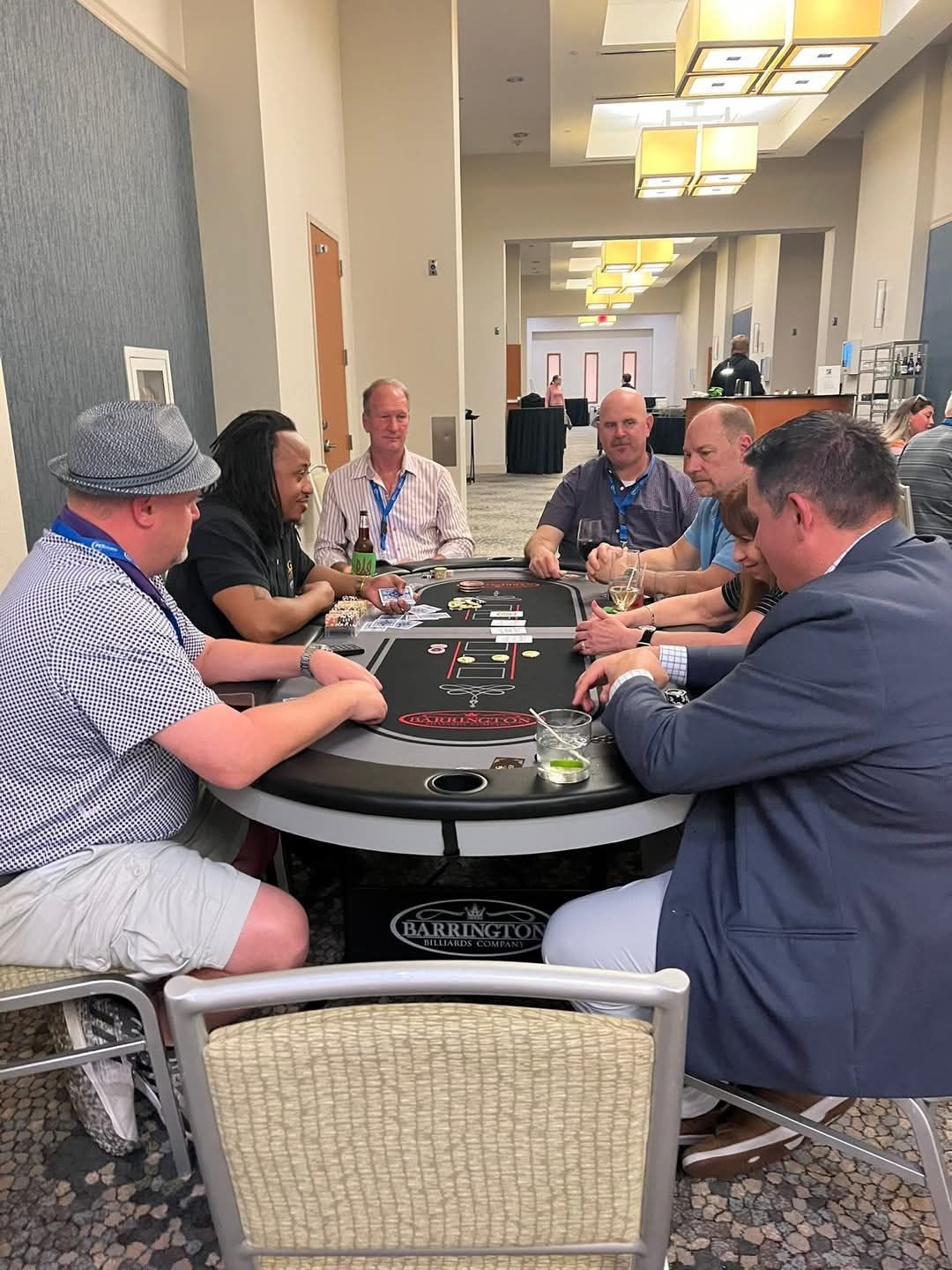 People playing cards around a casino table in a bright indoor lounge