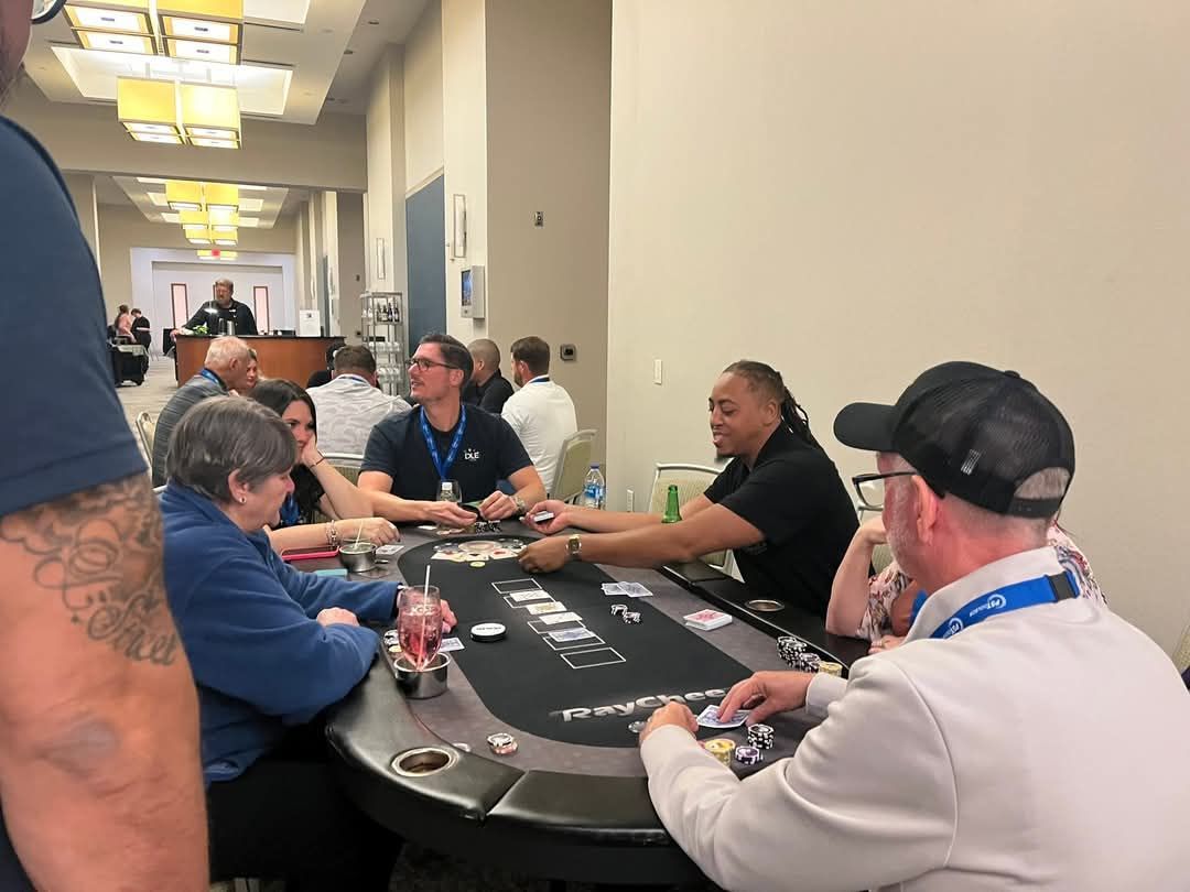 People seated at a casino blackjack table in a bright hallway, with chips and cards on the table.