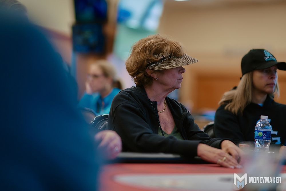 People seated at a table in a meeting, with a woman in a hat in the foreground