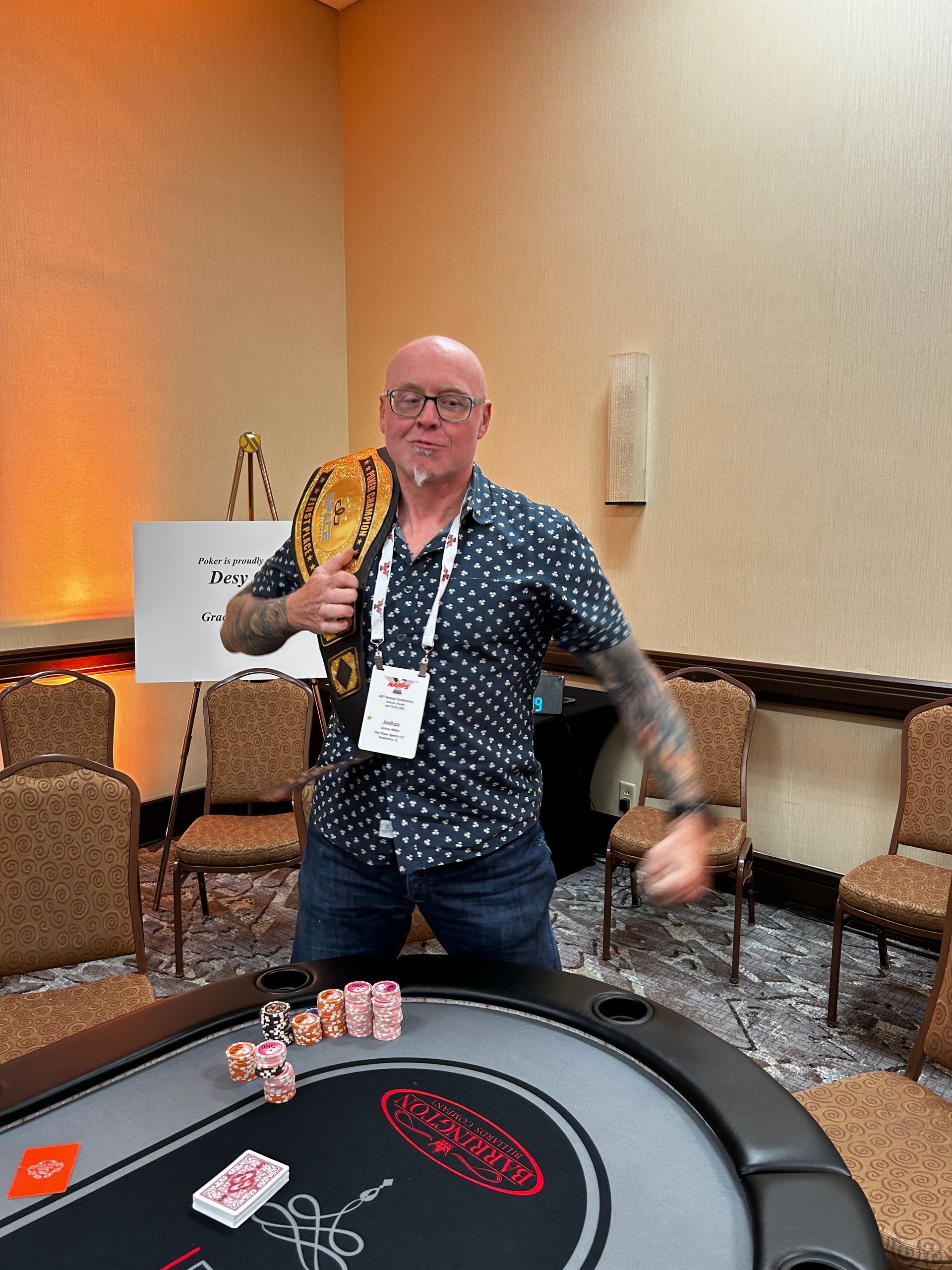 Man spinning a wooden paddle at a casino table, mid-gesture in a carpeted lounge area.