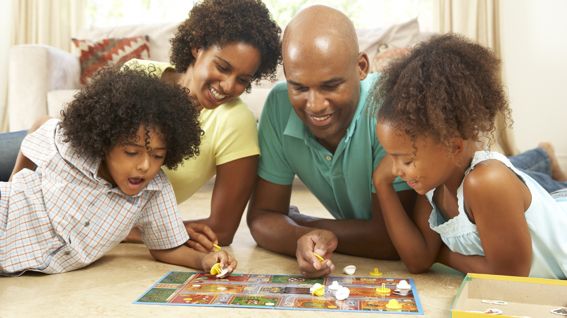 A family is laying on the floor playing a board game.
