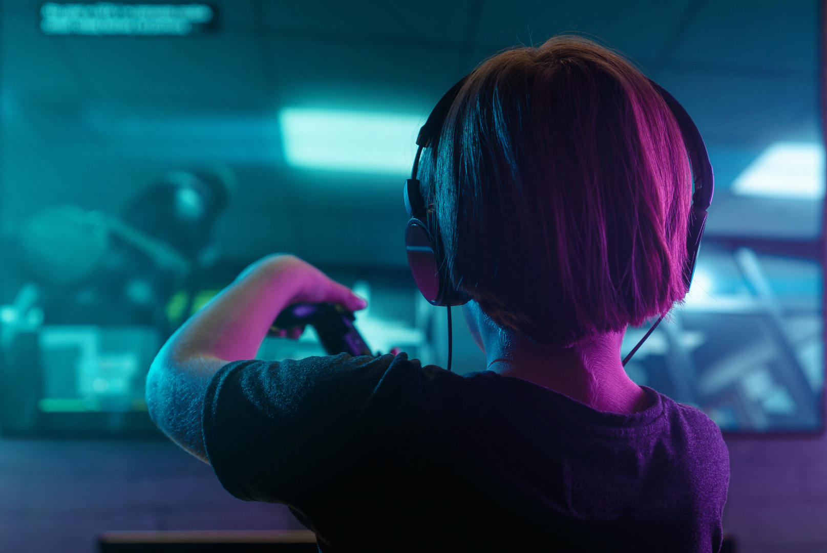 A young boy wearing headphones is playing a video game on a computer.