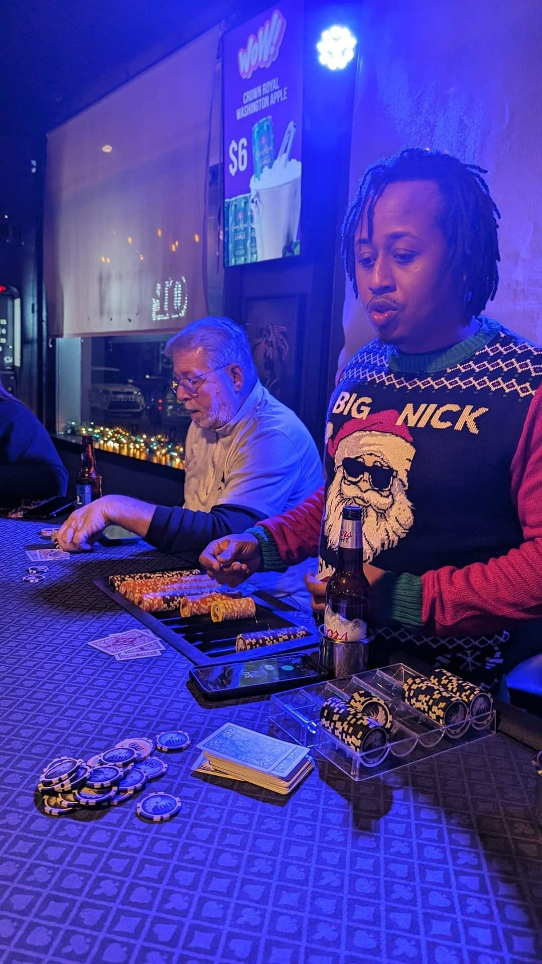Two people at a dimly lit restaurant table, one serving food near a plate and stacks of cash.