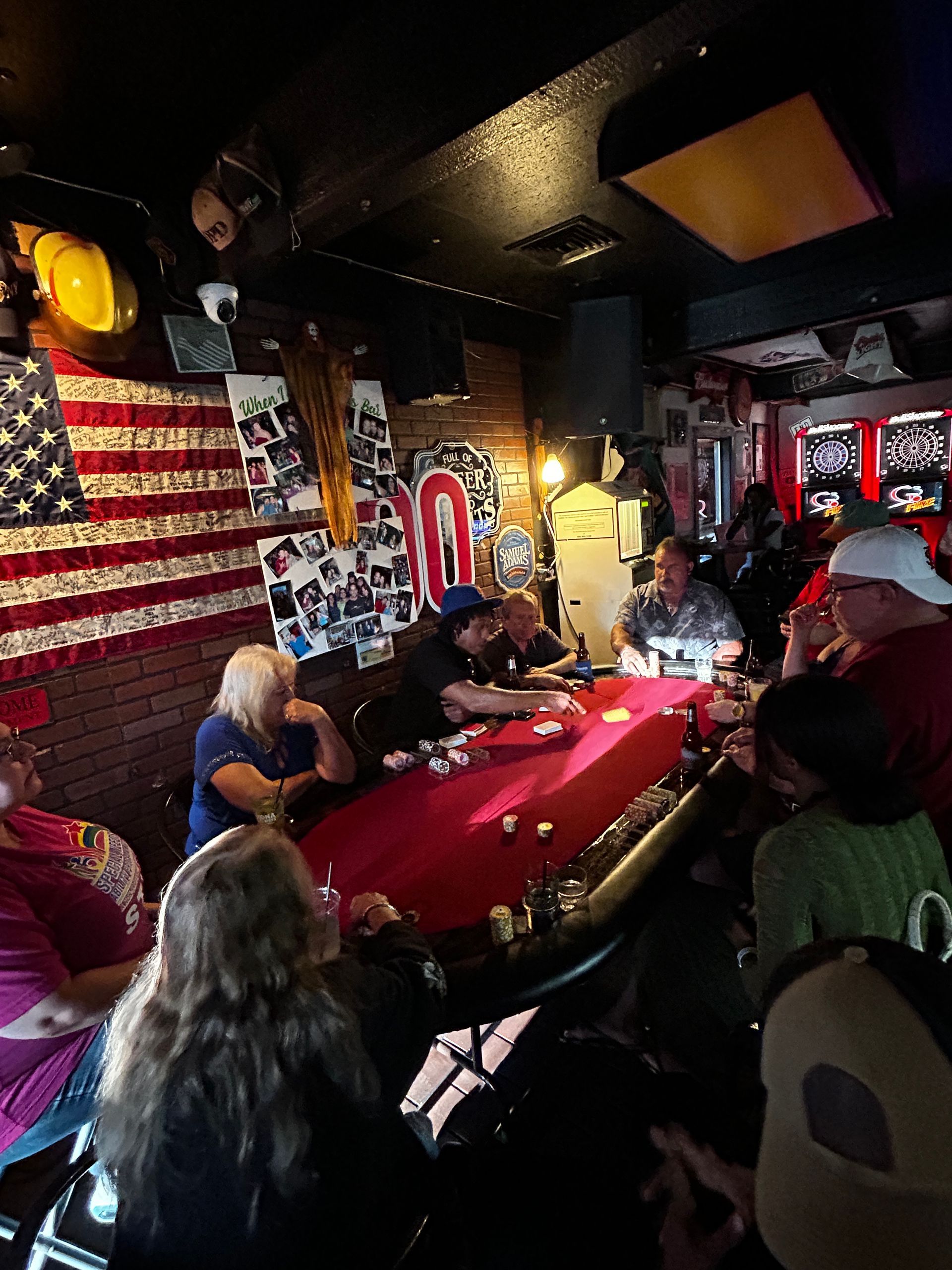 People seated around a red table in a dimly lit room with American flag wall decor and posters