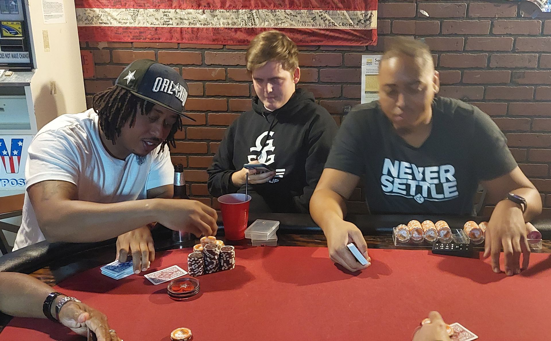 Three people sitting at a red table, eating and looking at food in a casual indoor setting.
