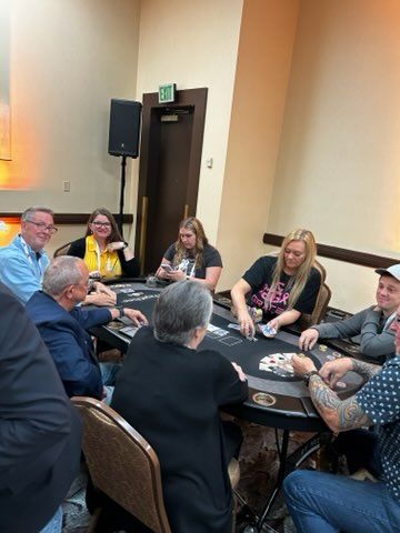 People seated around a table in a meeting room, playing a card game and talking.