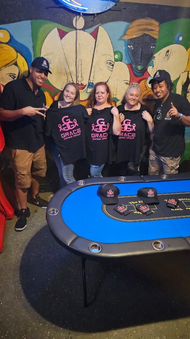Four people pose behind a blue mini golf hole in a colorful mural-lit indoor setting