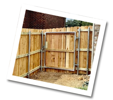 Wooden gate and fence with metal posts, next to brick building.