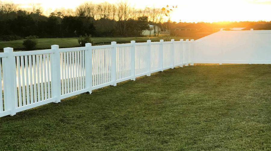 White vinyl picket fence installed around a large backyard