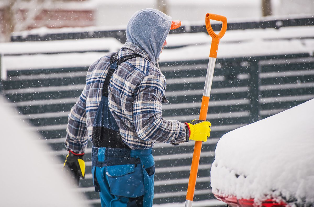 A man is shoveling snow from a car.