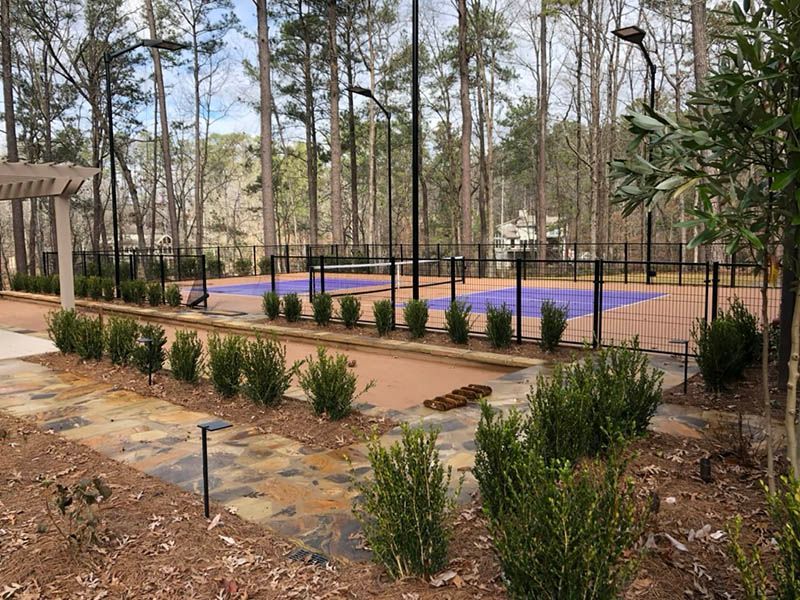 A tennis court in the middle of a forest surrounded by trees.
