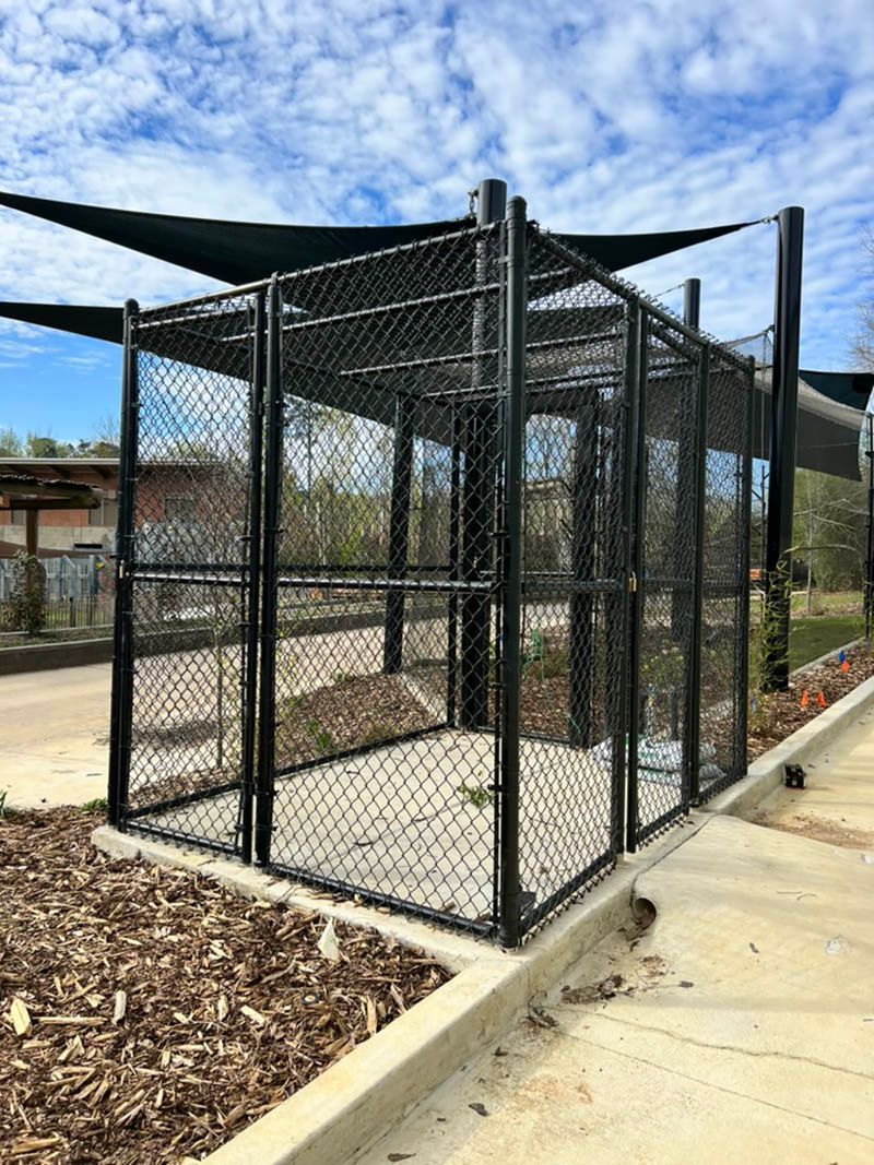 A black chain link fence is sitting next to a sidewalk.