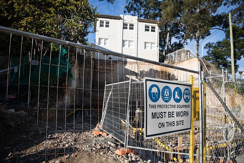 A construction site with a fence and a sign that says `` must be worn on this site ''.