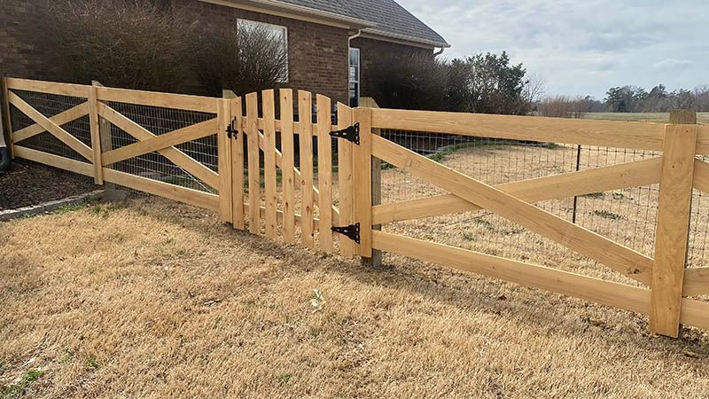 A wooden fence with a gate in front of a house.