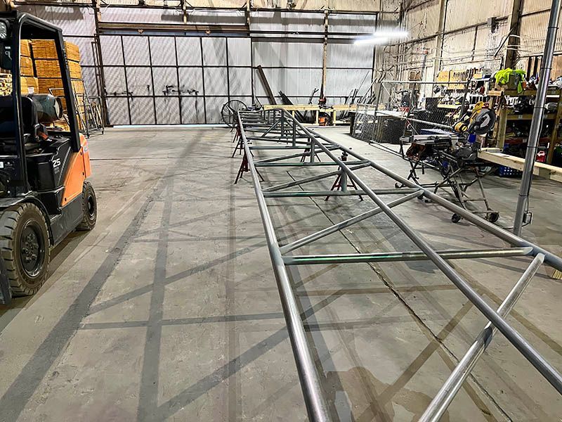 A forklift is driving through a warehouse filled with metal pipes.