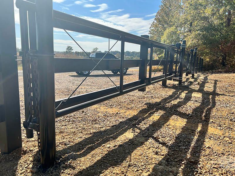 A truck is parked behind a metal fence in a gravel lot.