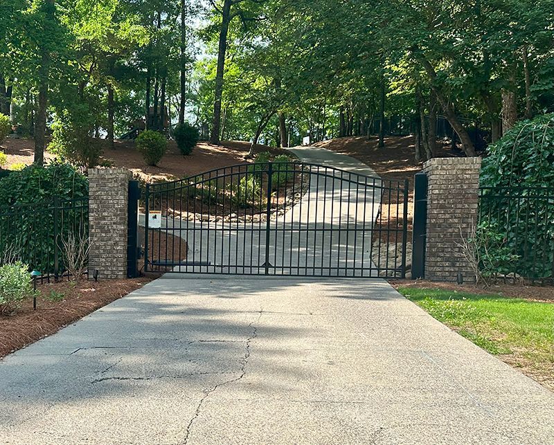 A driveway with a gate in the middle of it leading to a house.