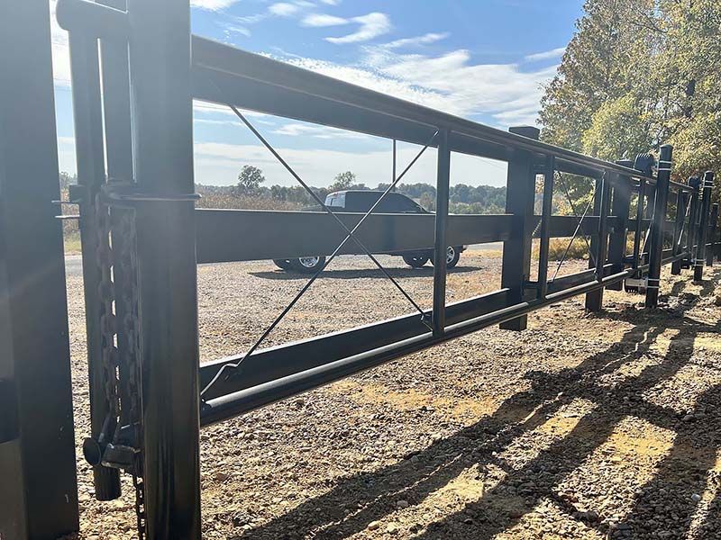 A truck is parked behind a metal gate in a dirt field.