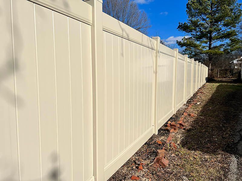 A white vinyl fence is sitting in the middle of a yard.