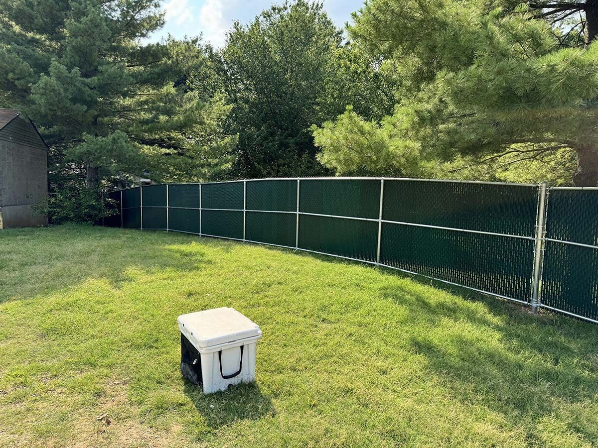 A white box is sitting in the grass in front of a fence.