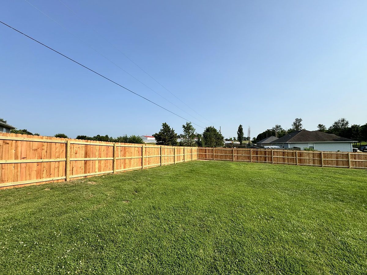 A wooden fence surrounds a lush green yard.