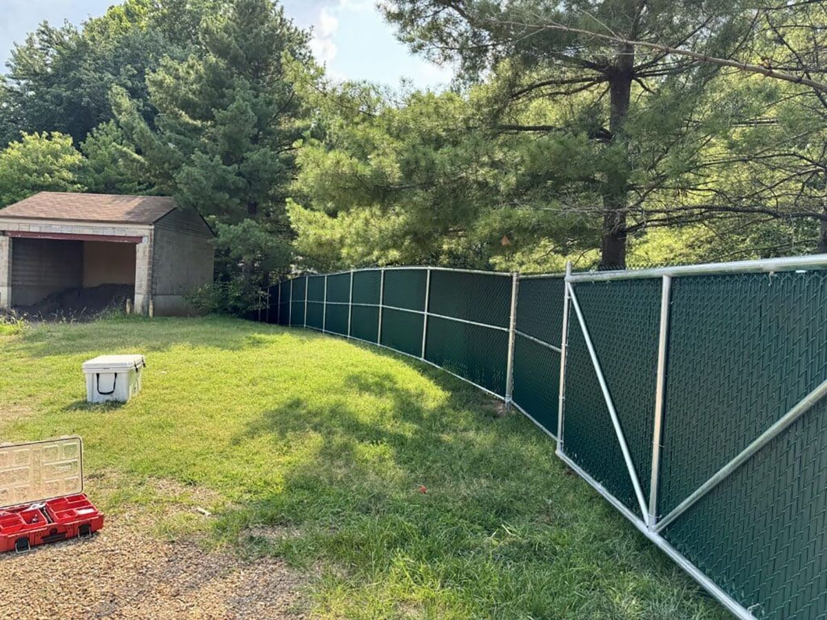 A green fence is sitting in the middle of a grassy field.