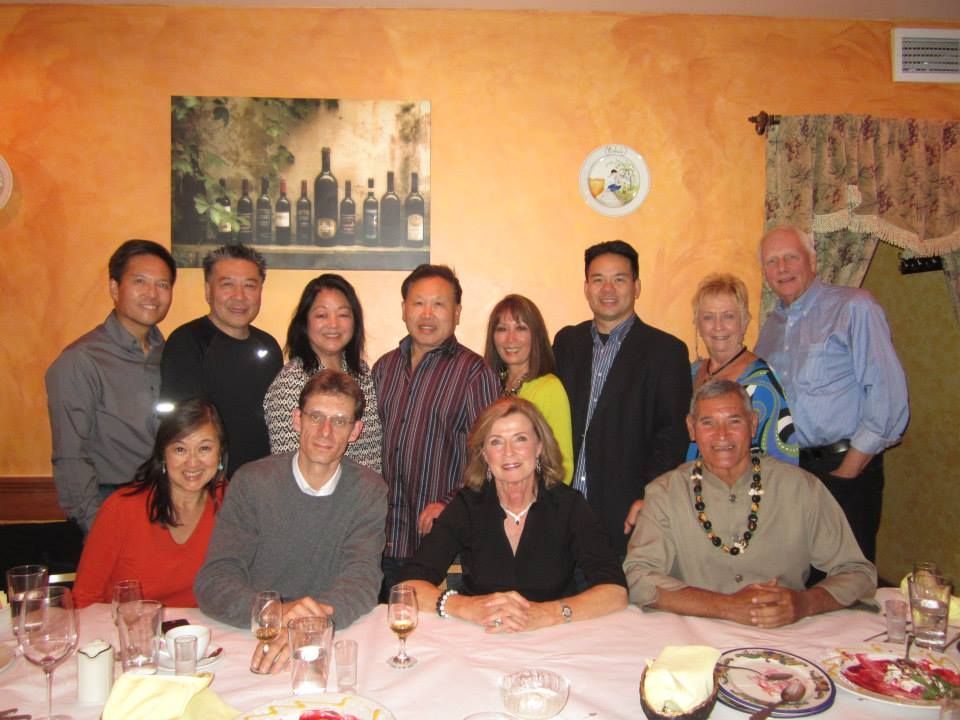 Group of people posing together at a table in a restaurant with warm-toned walls. 